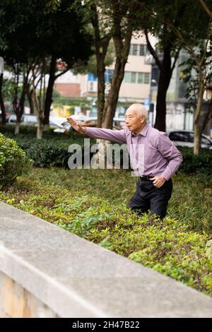 WENZHOU, ZHEJIANG, CHINA - 23. Okt 2021: Ein älterer Mann praktiziert Tai Chi in einem Park Stockfoto