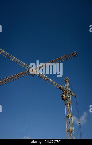 Zwei hohe gelbe Turmdrehkrane, über blauem Himmel Hintergrund Stockfoto