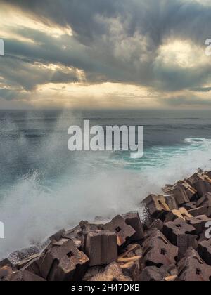 Stapel von großen Betonwürfeln, die ein Wellenbrecher bilden; stürmisches Meer im Hintergrund Stockfoto