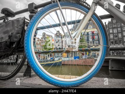 Niederlande. Fahrradfahren am Amsterdamer Ufer aus nächster Nähe. Schwarz-Weiß-Foto von der Außenseite der Felge, Farbfoto von innen Stockfoto