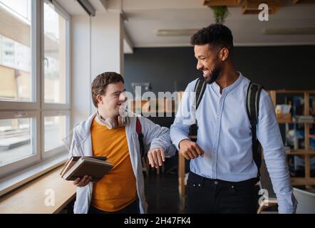 Junger glücklicher Mann mit Down-Syndrom und seinem Mentoring-Freund, der in der Schule Erfolge feiert. Stockfoto