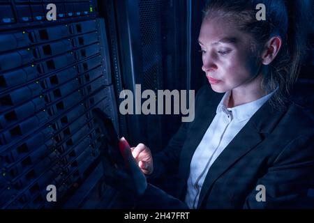 Ingenieurin, die im Rechenzentrum durch Server-Storage-Racks arbeitet Stockfoto
