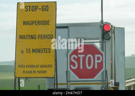 Stop Go Straßenschild und rote Ampel, um den Verkehr auf einer Autobahn zu kontrollieren, die in Südafrika repariert wird Stockfoto