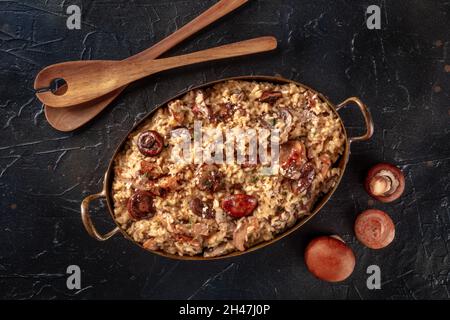 Risotto ai funghi, Pilzreis, darüber liegende flache Lage auf einem schwarzen Schieferhintergrund geschossen Stockfoto