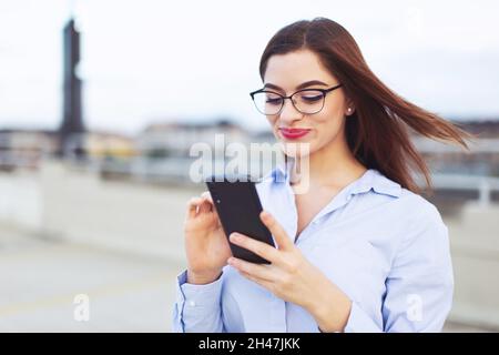 Junge Rotschopf Nerd kaukasischen Geschäftsfrau mit Smartphone im Freien Stockfoto