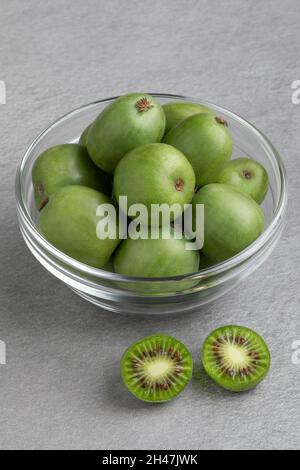 Glasschüssel mit frischen ganzen und halbierten Kiwi-Beeren aus der Nähe Stockfoto