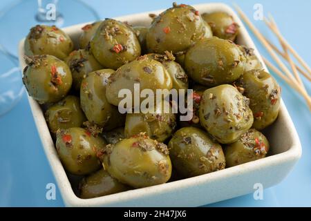 Schüssel mit griechischen grünen Oliven und Gewürzen aus nächster Nähe Stockfoto
