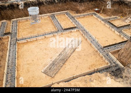 Gründung eines zukünftigen Hauses. Gießfundament mit Zement auf Baustelle mit Kran, Luftaufnahme. Stockfoto