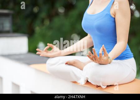 Zugeschnittenes Bild einer Frau, die morgens in Lotusposition im Freien meditiert Stockfoto