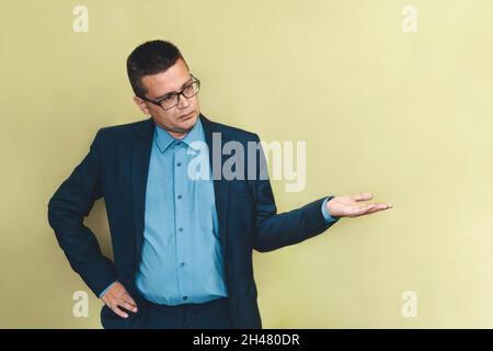 Geschäftsmann hält etwas ohne Thema. Mann in einem blauen Anzug zeigt auf die Seite. Speicherplatz kopieren. Stockfoto
