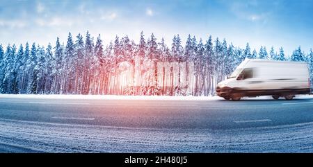 Weißer Van, der bei Schneefall auf einer rutschigen Asphaltstraße fährt Stockfoto