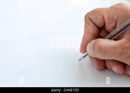 Menschliche Hand unterzeichnet leeres weißes Blatt Papier mit Stift. Eine Hand mit einem Stift in Nahaufnahme kennzeichnet ein leeres Papierdokument. Platz für Text und Design kopieren Stockfoto