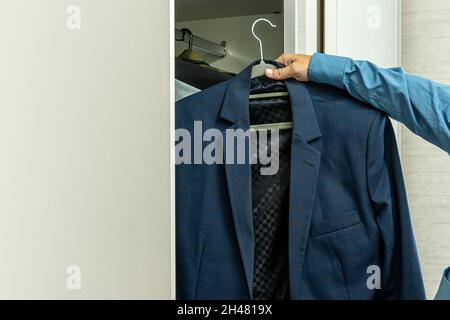 Geschäftsmann, der sich zur Arbeit kleidet. Ein junger Geschäftsmann wählt eine Jacke. Kleiderordnung bei der Arbeit. Stockfoto