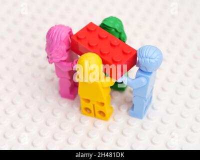 Tambow, Russische Föderation - 17. Oktober 2021 vier monochrome Lego-Minifiguren mit einem roten Lego-Stein. Weißer Hintergrund. Studioaufnahme. Stockfoto