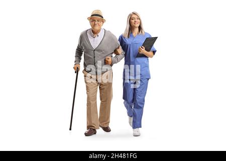 Ganzkörperportrait einer jungen Krankenschwester in blauer Uniform, die einem älteren Mann hilft, der auf weißem Hintergrund isoliert ist Stockfoto