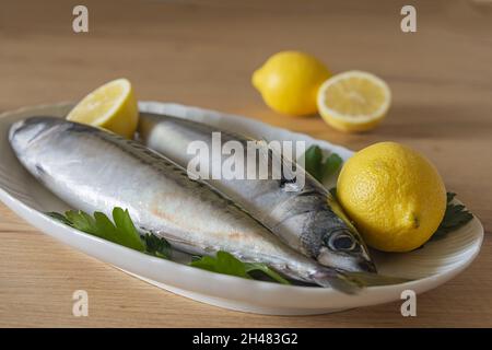 Due sgombri nel piatto bianco con limone su tavolo di legno 8 Stockfoto