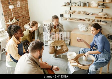 High-Angle-Ansicht auf verschiedene Gruppe von Menschen in Töpferwerkstatt in gemütlichen Studio, kopieren Raum Stockfoto