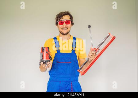 Ein Fliesenleger, ein Fliesenspezialist, hält einen Fliesenschneider in den Händen Stockfoto