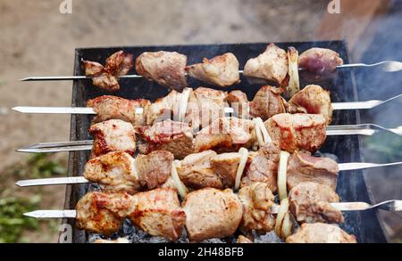 Marinierter Schaschlik, der auf einem Barbecue-Grill über Holzkohle zubereitet wird. Traditioneller russischer Schaschlik auf einem Grillspieß Stockfoto