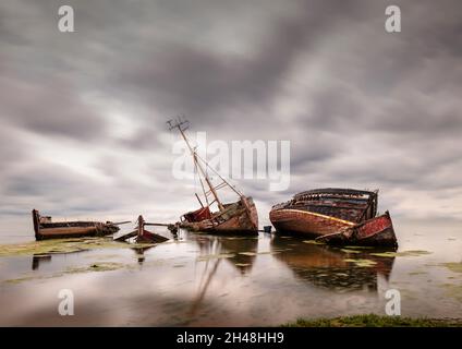 Wrackboote und Lastkähne liegen verlassen und teilweise an der Küste bei Pin Mill am Fluss Orwell, Suffolk, England, unter Wasser. Stockfoto