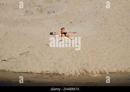 13.08.2013. Russland. Region Moskau. Alltag. Einsamer Mann sonbacht an einem heißen Tag am Strand. Stockfoto