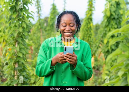 Aufnahme einer glücklichen afrikanischen Farmerin in Nigeria mit ihrem Smartphone Stockfoto