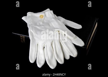 Bibel und weiße Handschuhe isoliert auf schwarzem Hintergrund Stockfoto