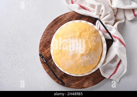 Roher Hefeteig mit Kürbis in weißer Schüssel mit Handtuch auf dem bemehlten Küchentisch bedeckt, Rezeptidee. Konzept Hausbacken Brot, Brötchen oder Cinnabon o Stockfoto