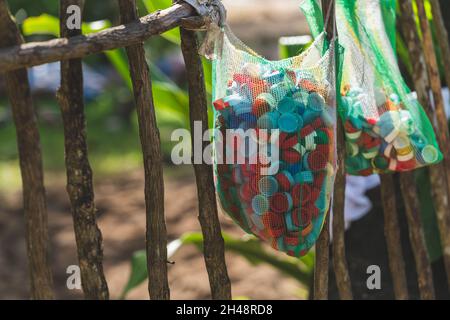 Viele Plastikflaschen-Kappen wurden in einem Beutel gesammelt. Müll, der die Erde verschmutzt. Stockfoto