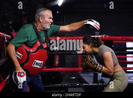 Die britische Profiboxerin Ruqsra Begum, die während einer Trainingseinheit im KO Boxing Gym in Bethnal Green, East London, mit Trainer Steve Walters, spezifische Kombinationen, die sie im Kampf einsetzen wird, Vor ihrem Superflyweight-Kampf gegen Tasha Boyes am Freitag, dem 5. November. Ausgabedatum: Montag, 1. November 2021. Stockfoto