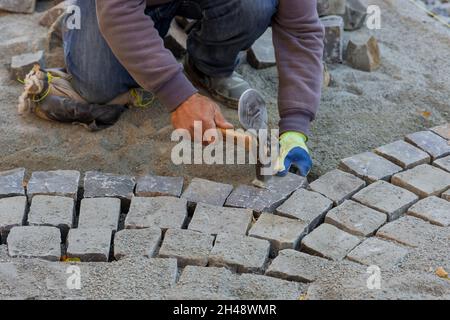 Pflaster mit Granitsteinen, Arbeiter mit industriellen Pflastersteinen für Pflaster Straße Stockfoto