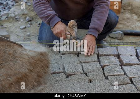 Pflaster mit Granitsteinen, Arbeiter mit industriellen Pflastersteinen für Pflaster Straße Stockfoto