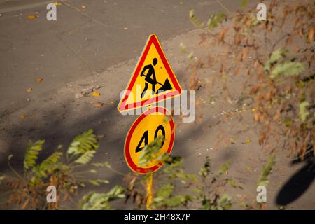 Straßenschild und -Symbol. Verkehrsschild auf dem Hintergrund der Straße. Straßenschilder. Straßenreparatur und Geschwindigkeitsbegrenzung für Autos. Fahrerwarnschild für sicheres dri Stockfoto