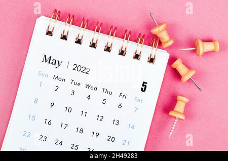 Nahaufnahme des Tischkalenders Mai 2022 mit Holznadel auf rosa Hintergrund. Stockfoto