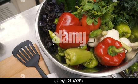 Frisches Rohes Frühlingsgemüse. Clip. Essen Vegetarisch Hintergrund. Tomaten, Gurke, Radieschen, Salatblätter im Metallkorb. Draufsicht Stockfoto