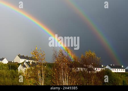 Doppelter Regenbogen über dem sozialen Wohnungsbau in Ardara, County Donegal, Irland Stockfoto