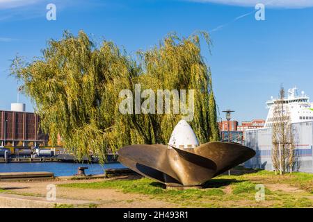 Ein bronzener Schiffspropeller vor einer Trauerweide im Herbst im Kieler Hafen Stockfoto