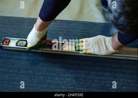 Die Bänder des Dachmaterials, schneidet der Meister die Dachmaterialien aus der Rolle, der Abdichtung des Bodenbelags, den Reparaturarbeiten. Stockfoto