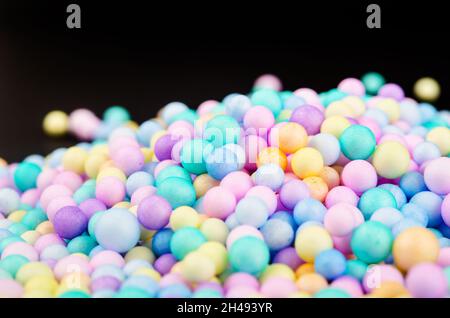 Schaumstoffperlen in verschiedenen Farben bunt auf schwarzem Hintergrund. Stockfoto