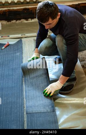 Die Bänder des Dachmaterials, schneidet der Meister die Dachmaterialien aus der Rolle, der Abdichtung des Bodenbelags, den Reparaturarbeiten. Stockfoto