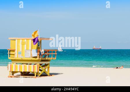 Panoramablick auf Miami Beach mit einer hölzernen Rettungsschwimmerstation mit Warnflaggen. Im Hintergrund segeln Boote Stockfoto