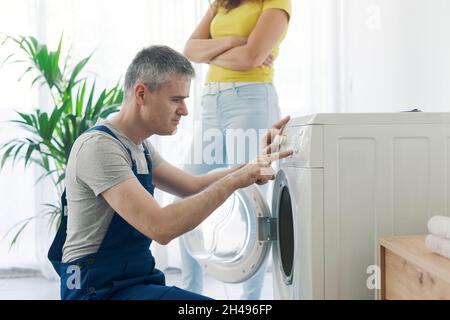 Professioneller Klempner, der eine Waschmaschine repariert, überprüft die Einstellungen auf dem Bedienfeld Stockfoto