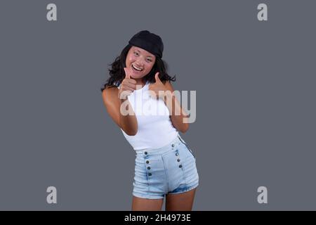 Ziemlich junges asiatisches Mädchen mit Bandana, Daumen nach oben als Zeichen der Zustimmung und großes Lächeln Stockfoto