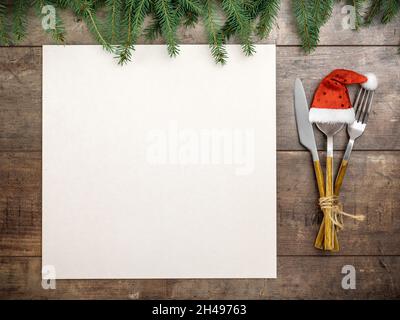 Weihnachtstisch mit Dekoration und Mockup weihnachtsmenü. Blick von oben auf rustikalen Esstisch Einstellung. Weihnachtsmenü auf leerem Papier Stockfoto