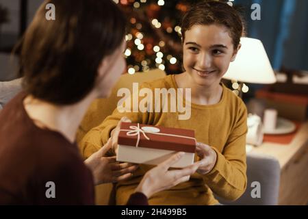 Glückliches Mädchen erhält ein schönes Weihnachtsgeschenk von ihrer Mutter Stockfoto
