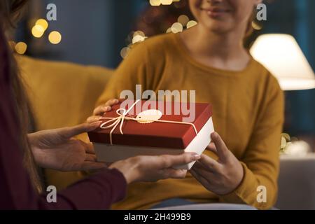 Glückliches Mädchen erhält ein schönes Weihnachtsgeschenk von ihrer Mutter Stockfoto