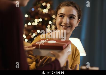 Glückliches Mädchen erhält ein schönes Weihnachtsgeschenk von ihrer Mutter Stockfoto