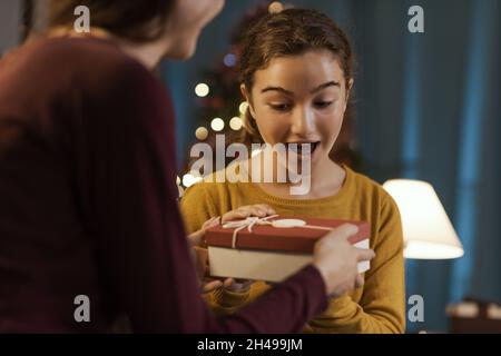 Glückliches Mädchen erhält ein schönes Weihnachtsgeschenk von ihrer Mutter Stockfoto