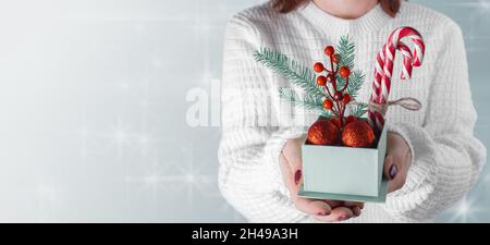 Nahaufnahme der weiblichen Hände, die ein kleines Geschenk halten. Die Hände der Frau halten weihnachten oder Neujahr dekorierte Geschenkbox. Banner, Kopierraum Stockfoto
