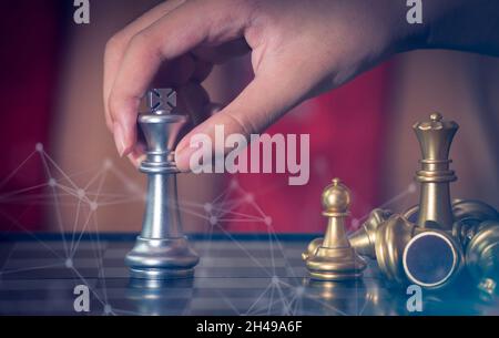 Hand Geschäftsmann bewegen den goldenen Ritter Schach kämpfen silbernen Ritter mit Feuer Funken Schach auf dem Schachbrett erfolgreich im Wettbewerb. Manag Stockfoto